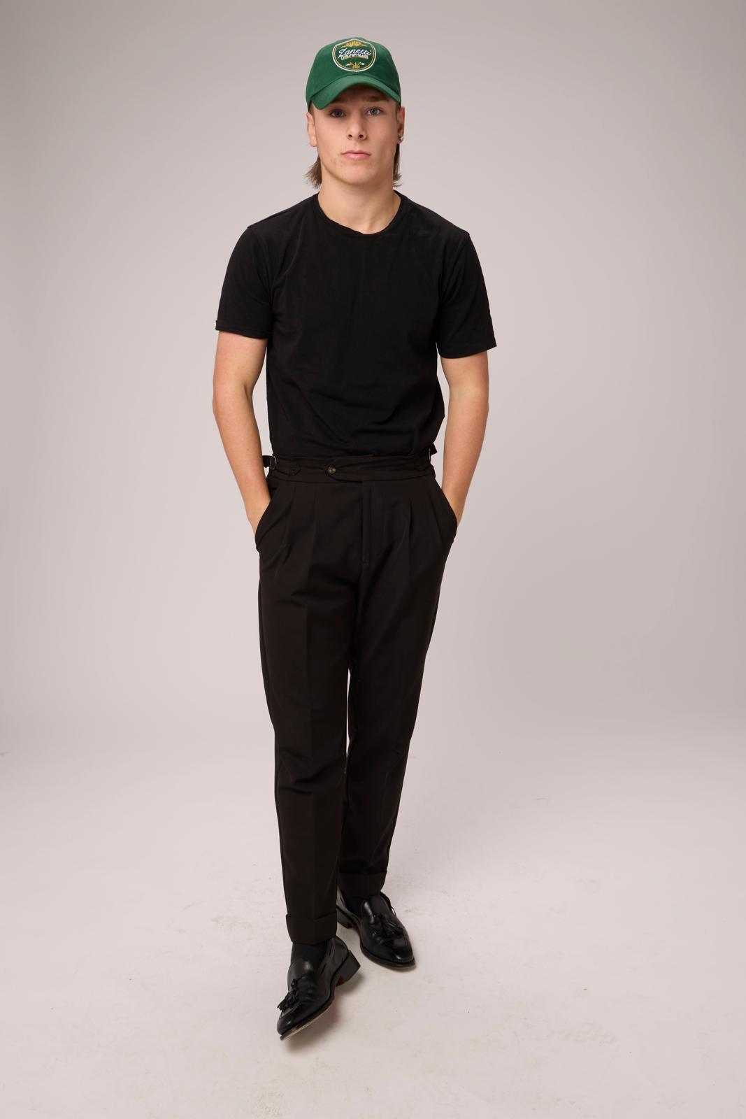 Model in the Jaguar Green crest cap, black tee and pleated black trousers